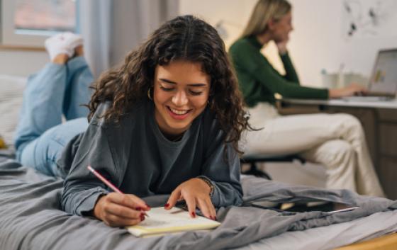 student working on her bed